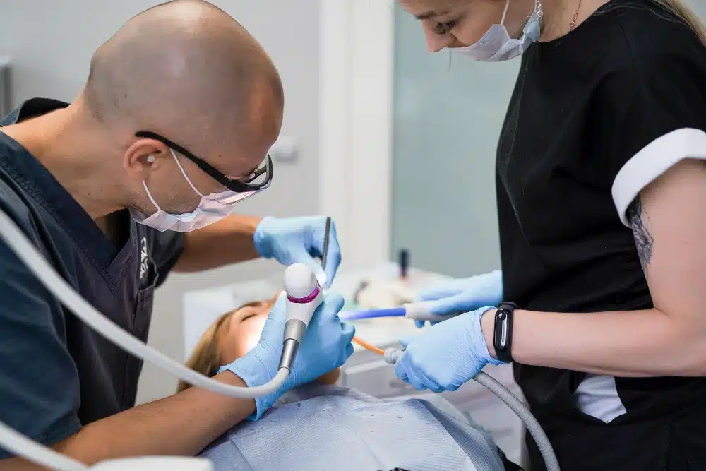 Dentist performing root canal procedure with assistant, showcasing dental tools and patient care at Hastings Dental Centre.
