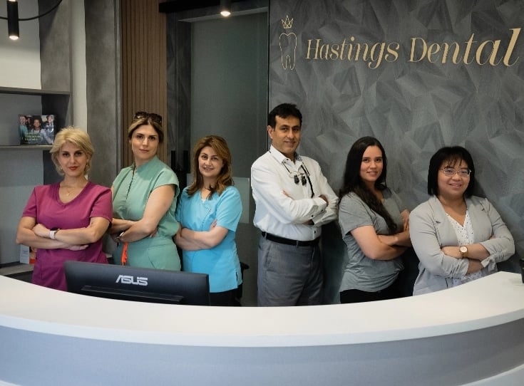 Hastings Dental Center staff members standing at the reception area, showcasing a welcoming dental team ready to assist new patients with forms and inquiries.