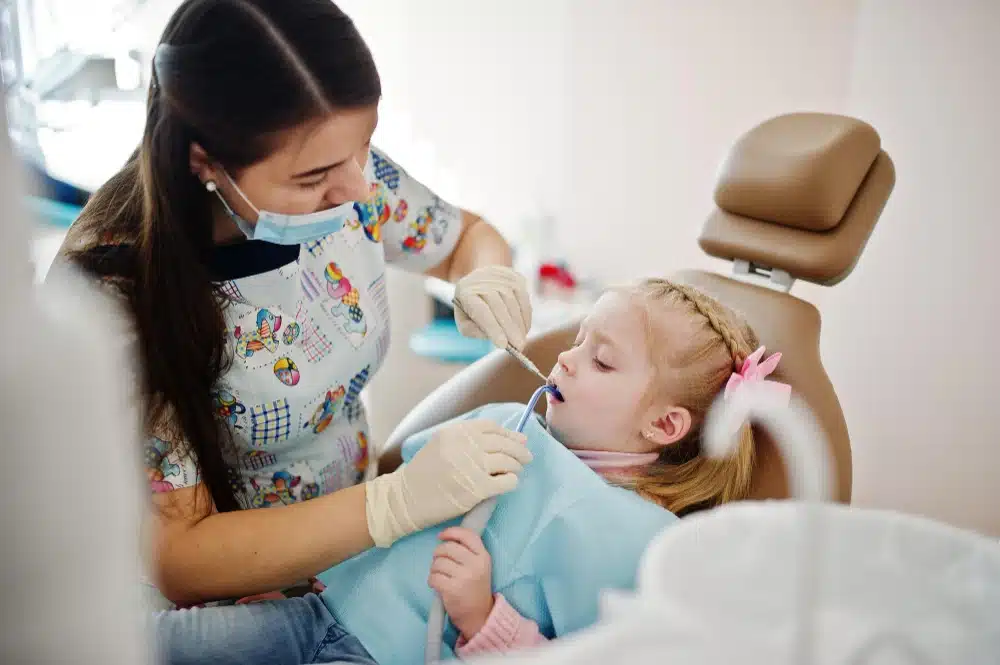 Child receiving dental care from a hygienist in a pediatric dental clinic, emphasizing compassionate and gentle treatment at Hastings Dental Center.