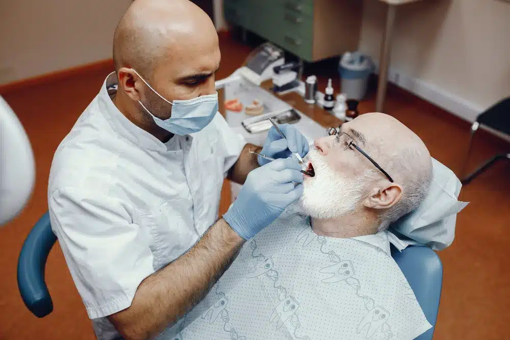 Dentist performing dental examination on elderly patient in dental clinic, showcasing personalized dental care and implant consultation at Hastings Dental Center.