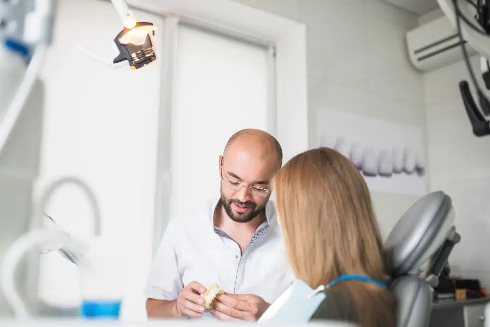 Dentist explaining porcelain veneer procedure to patient in modern dental office setting.