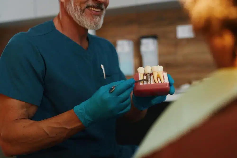 Dental professional demonstrating various dental implants using a model, emphasizing tooth replacement options at Hastings Dental Center.